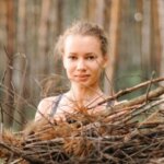 teenage girl with pimple skin collect branches firewood for a campfire while traveling through a summer forest in nature. young happy people survivalist traveler and local travel on great outdoors